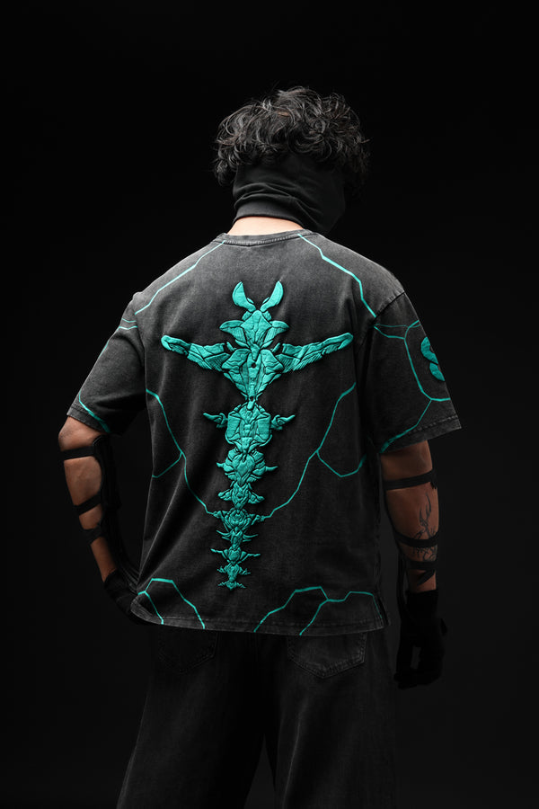 Person wearing a black t-shirt with teal designs on the back against a black background